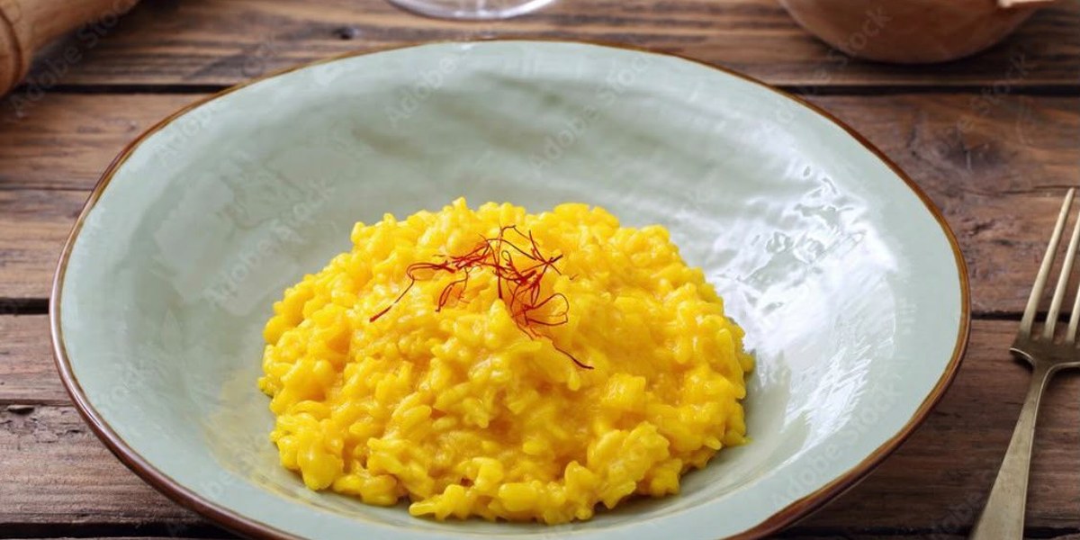 Un piatto di risotto allo zafferano con qualche stimma sopra.